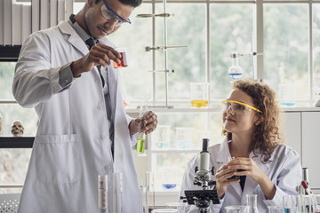 Team of Medical Research Scientist Conducts Experiments in Laboratory with Microscope, Test Tubes, Micropipette and other equipment.