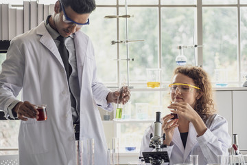 Team of Medical Research Scientist Conducts Experiments in Laboratory with Microscope, Test Tubes, Micropipette and other equipment.