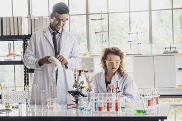Team of Medical Research Scientist Conducts Experiments in Laboratory with Microscope, Test Tubes, Micropipette and other equipment.