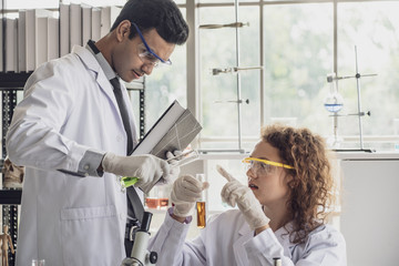 Team of Medical Research Scientist Conducts Experiments in Laboratory with Microscope, Test Tubes, Micropipette and other equipment.