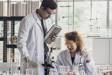 Team of Medical Research Scientist Conducts Experiments in Laboratory with Microscope, Test Tubes, Micropipette and other equipment.