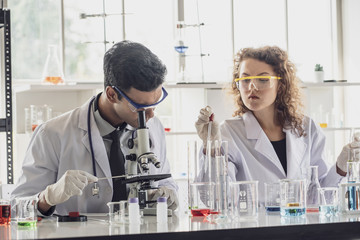 Team of Medical Research Scientist Conducts Experiments in Laboratory with Microscope, Test Tubes, Micropipette and other equipment.