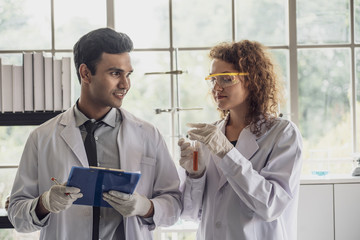 Team of Medical Research Scientist Conducts Experiments in Laboratory with Microscope, Test Tubes, Micropipette and other equipment.