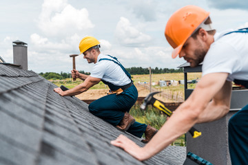 Selective focus of handsome handyman repairing roof with colleague © LIGHTFIELD STUDIOS