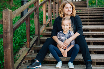 Mother and daughter having fun in the park. Happiness and harmony in family life.  Beauty nature scene with family outdoor lifestyle. Woman and cheerful little girl