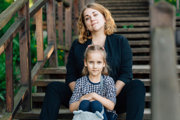 Mother and daughter having fun in the park. Happiness and harmony in family life.  Beauty nature scene with family outdoor lifestyle. Woman and cheerful little girl