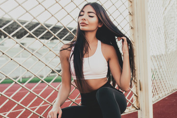 Beautiful fitness woman in sportswear posing near grid.