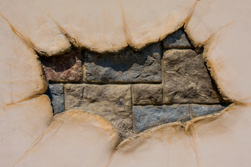 Torn covering of walls from glued stones. A hole in the whole canvas.