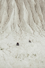 Man and woman sitting on sand in distance in the limestone quarry in Rummu. Estonia.