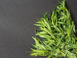 Bunch of fresh tarragon isolated on a black stone background. Top view