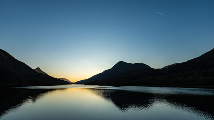 sunset on a clear calm day over loch leven near kinlochleven in the argyll region of scotland during autumn showing calm waters and golden hues