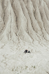 Tourist couple sitting together in the distance on a white sand geological and industrial district in Rummu. Estonia.