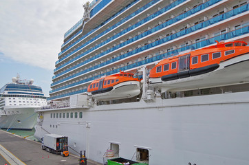Hafenarbeiter in Gabelstaplern beladen großes weißes Kreuzfahrtschiff Royal Princess Cruises im...