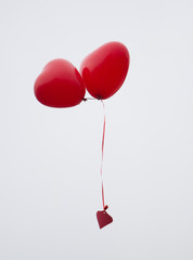 Zwei fliegende Luftballons in Herzform (rot)
