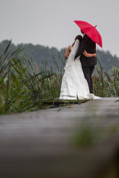Hochzeitspaar auf Bootsteg im Regen