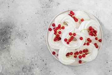 Fototapeta na wymiar Meringues in the form of rings with bunches of red currants on a white plate