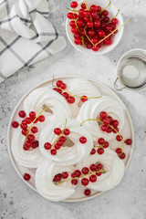 Meringues in the form of rings with bunches of red currants on a white plate