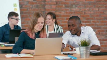 Caucasian Woman and African Man Work Together in Modern Loft Startup Office Team. Young Diverse Multiethnic Group of Authentic People Talk and Discuss Projects. 4K Medium Static Shot