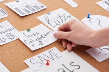 cropped view of woman holding card with loss calculation inscription on cork board