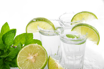 Tequila shot with juicy lime slice on white background