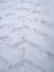 Fototapeta na wymiar A closeup view of ATV or all terrain vehicle tracks in fresh white snow in Wisconsin.