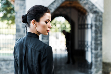 side view of attractive woman standing near building on funeral