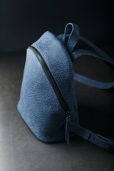 Blue backpack made of genuine leather on a dark background, handmade.