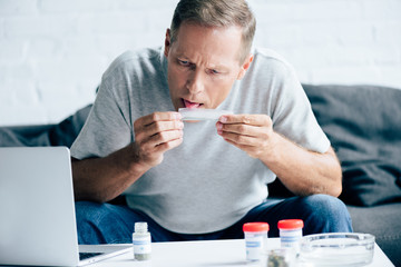 handsome man in t-shirt licking paper for blunt with medical cannabis