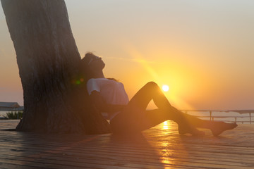 Profile of a woman silhouette watching sun on the beach at sunset.