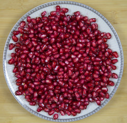 Background of red ripe pomegranate seeds on a plate. Raw organic fruits vegetables. Useful product.