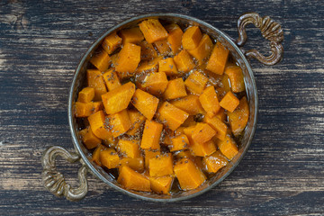 Baked yellow pumpkin with honey, anise, olive oil and spices on a plate on the wooden table. Vegetarian food. Closeup