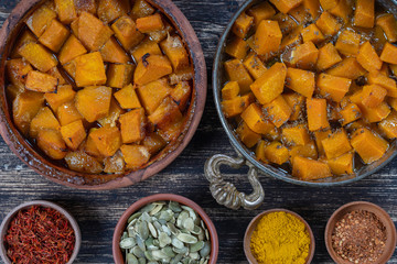 Baked yellow pumpkin with honey, anise, olive oil and spices on a plate on the wooden table. Vegetarian food. Closeup