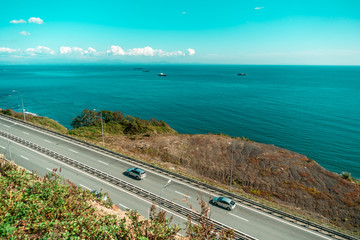 Fototapeta na wymiar Road by the sea with passing cars