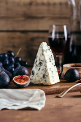 blue cheese, sweet fig fruits and grapes on a wooden board