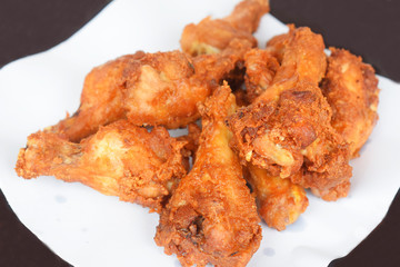 Fried chicken is placed in a white paper on the brown background. /Selective focus.