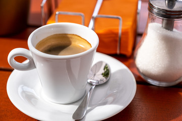 cup of coffee and sugar bowl on a wooden table in a cafe.