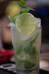 Refreshing mint cocktail mojito with rum and lime, cold drink or beverage with ice on white wooden background, top view