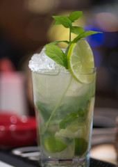 Refreshing mint cocktail mojito with rum and lime, cold drink or beverage with ice on white wooden background, top view