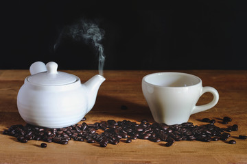 White Hot coffee cup with white pot and roasters bean on table.