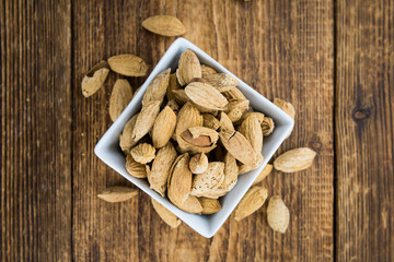 Roasted Almonds (in shell) on a wooden table (selective focus)