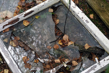 Old window frame with broken glass on the ground.