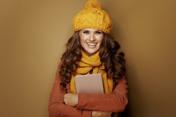 happy young woman hugging book isolated on beige