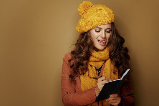 Woman Writing Goals In Notebook Against Beige Background