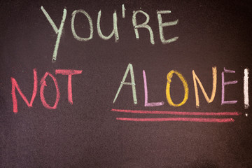 Fototapeta premium handwriting you are not alone on chalkboard with colorful chalk