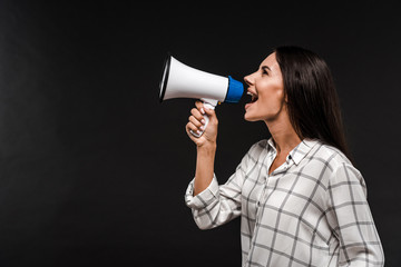 side view of cheerful woman screaming in megaphone isolated on black