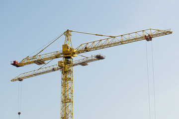 Several yellow high-rise construction cranes build multi-storey multi-apartment residential buildings using modern technologies of metal, concrete and brick according to the architectural design