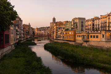 Colorful yellow and orange houses reflected in water river Onyar, in Girona, Catalonia, Spain.