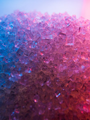 Fototapeta premium Heap of transparent white sugar crystals in mixed colour light. Macro photo