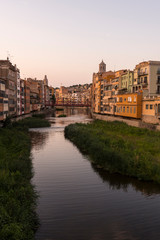 Colorful yellow and orange houses reflected in water river Onyar, in Girona, Catalonia, Spain.