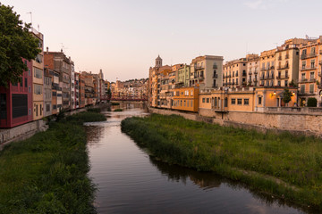 Colorful yellow and orange houses reflected in water river Onyar, in Girona, Catalonia, Spain.